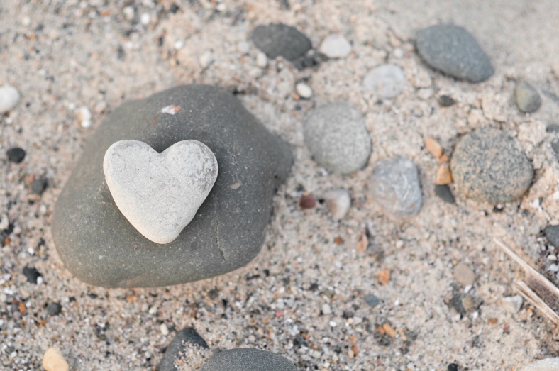 Heart-Shaped Stone with Other Rocks on Beach Sand